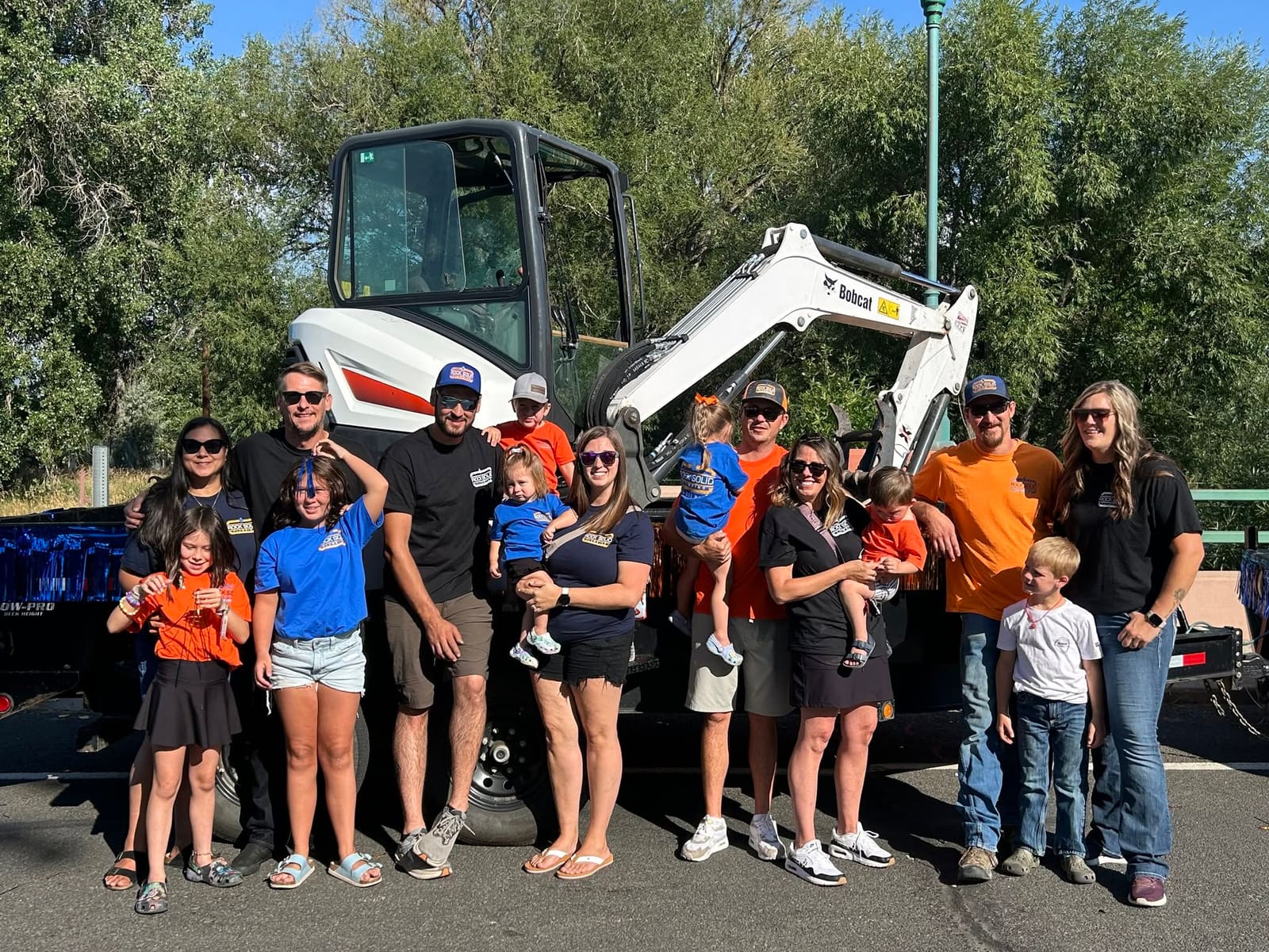 The extended Rock Solid Plumbing family gathered in front of company equipment